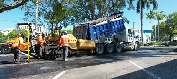 Paving contractor near me, 3-D Paving dumps a fresh truckload of asphalt into the paving machine to lay down a final life of asphalt paving