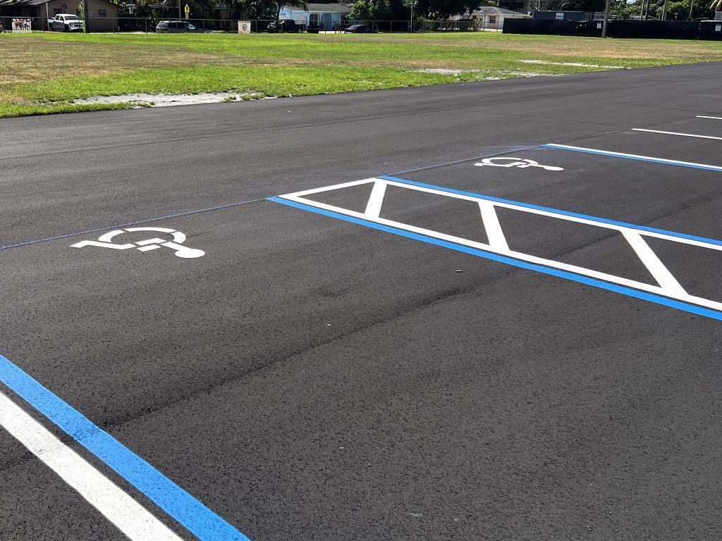Handicap parking stalls freshly painted onto newly laid asphalt parking lot for ADA compliance.