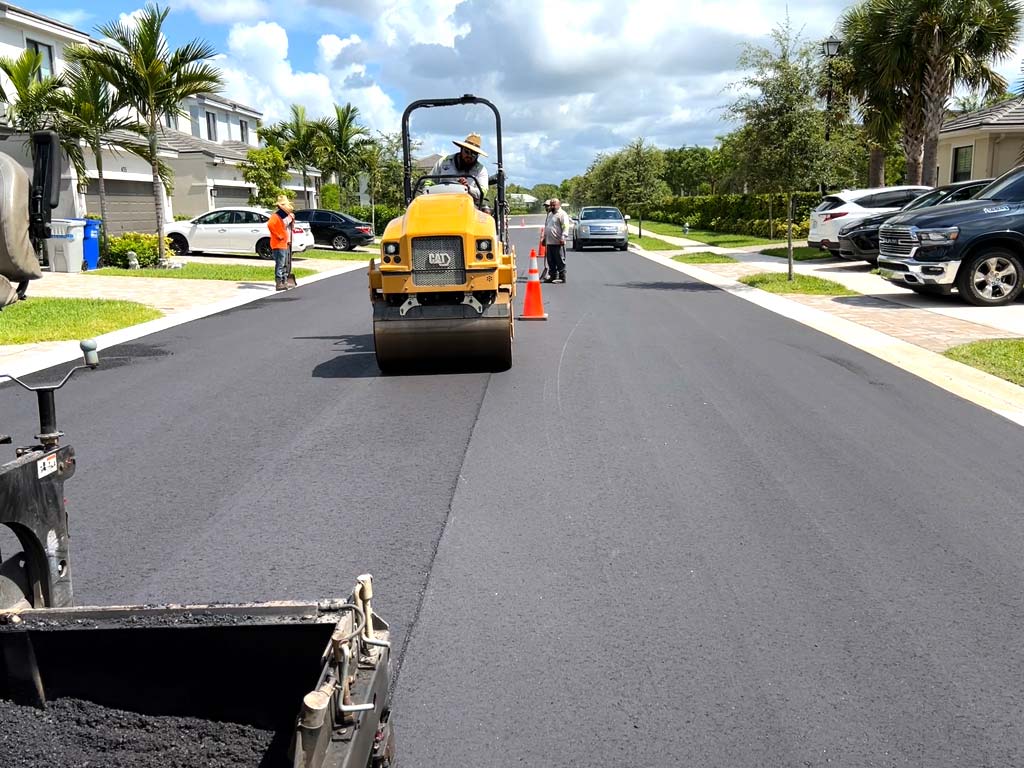 Heavy Caterpillar (Cat) asphalt paving roller machine compacts the freshly installed life of asphalt at an upscale residential community in Pompano Beach, FL by 3-D Paving and Sealcoating.