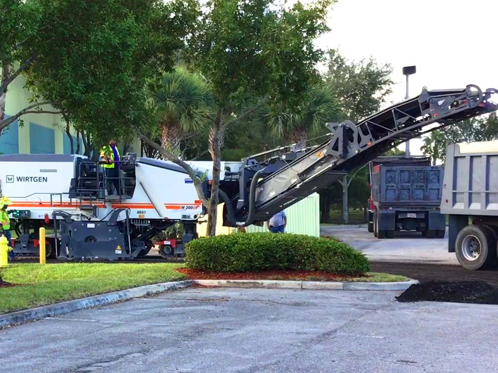 Asphalt Milling is the process of removing the top layer of asphalt that's damaged in preparation for a new layer of asphalt to be installed at a local business. Large asphalt milling machine pictured here by 3-D Paving & Sealcoating in Coral Springs, FL.