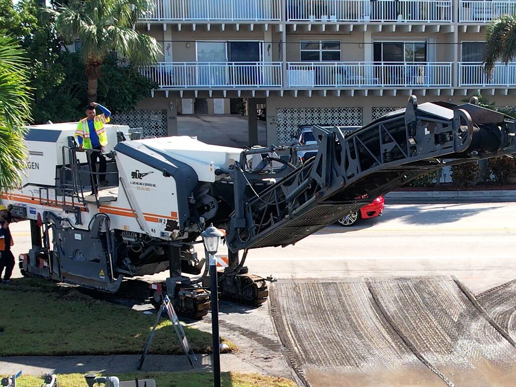 Asphalt milling machine, milling the top layer of asphalt from a residential communities parking lot in West Palm Beach. The debrit generated is known as asphalt millings which can be recycled into new pavement surfaces. Providing excellence in blacktop paving for decades in South Florida.