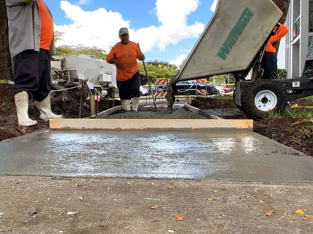 Concrete sidewalk repair being executed by removing the damaged area caused by underground tree roots and replacing the damaged sidewalk flags with new segments.