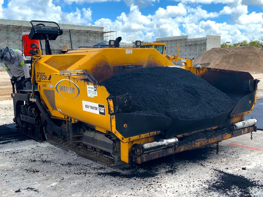 Asphalt paving machine with a filled hopper of hot mix asphalt at a commercial paving project by 3-D Paving and Sealcoating in Coral Springs, FL. Have asphalt problems? We have asphalt solutions. With asphalt paving systems from the experts.