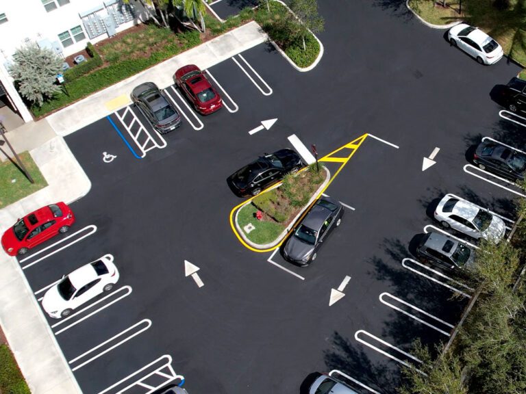 overhead view of a South Florida HOA condo parking lot with crosswalks, parking lot signage, directional arrows, ada compliance modifications like handicap parking stalls, yellow and white lines and more. Freshly paved, sealcoating & striped using vinyl striping at a parking lot in Coral Springs, FL by 3-D Paving and Sealcoating. South Florida's Commercial Paving Experts. April 2023.
