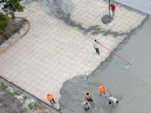 Aerial view of a construction crew installing a concrete slab for a new concrete slab for a concrete parking lot.. 3-D Paving